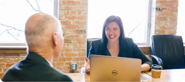 a man and a woman sitting at a table with a laptop